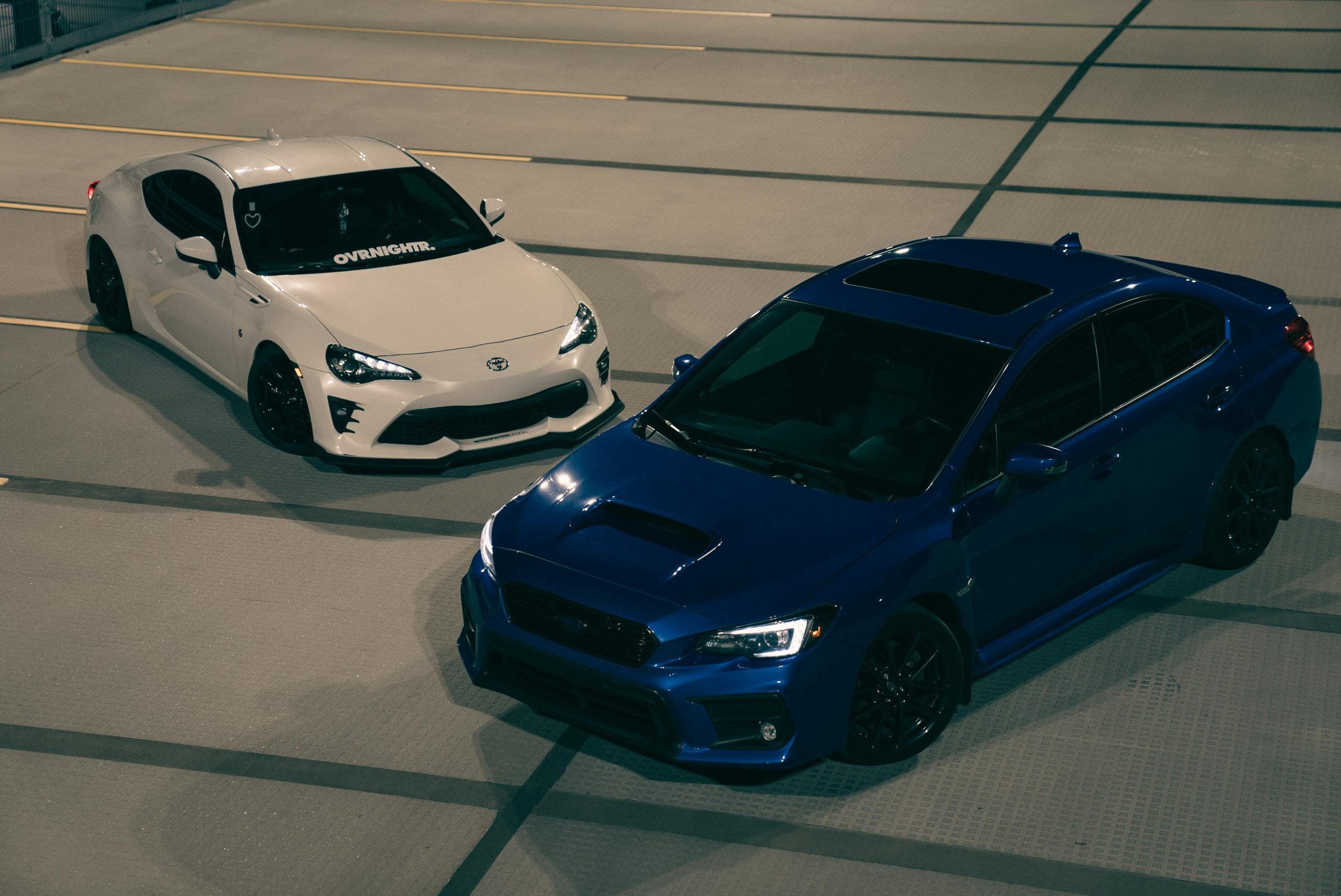 Nighttime Display of Blue and White Sports Cars