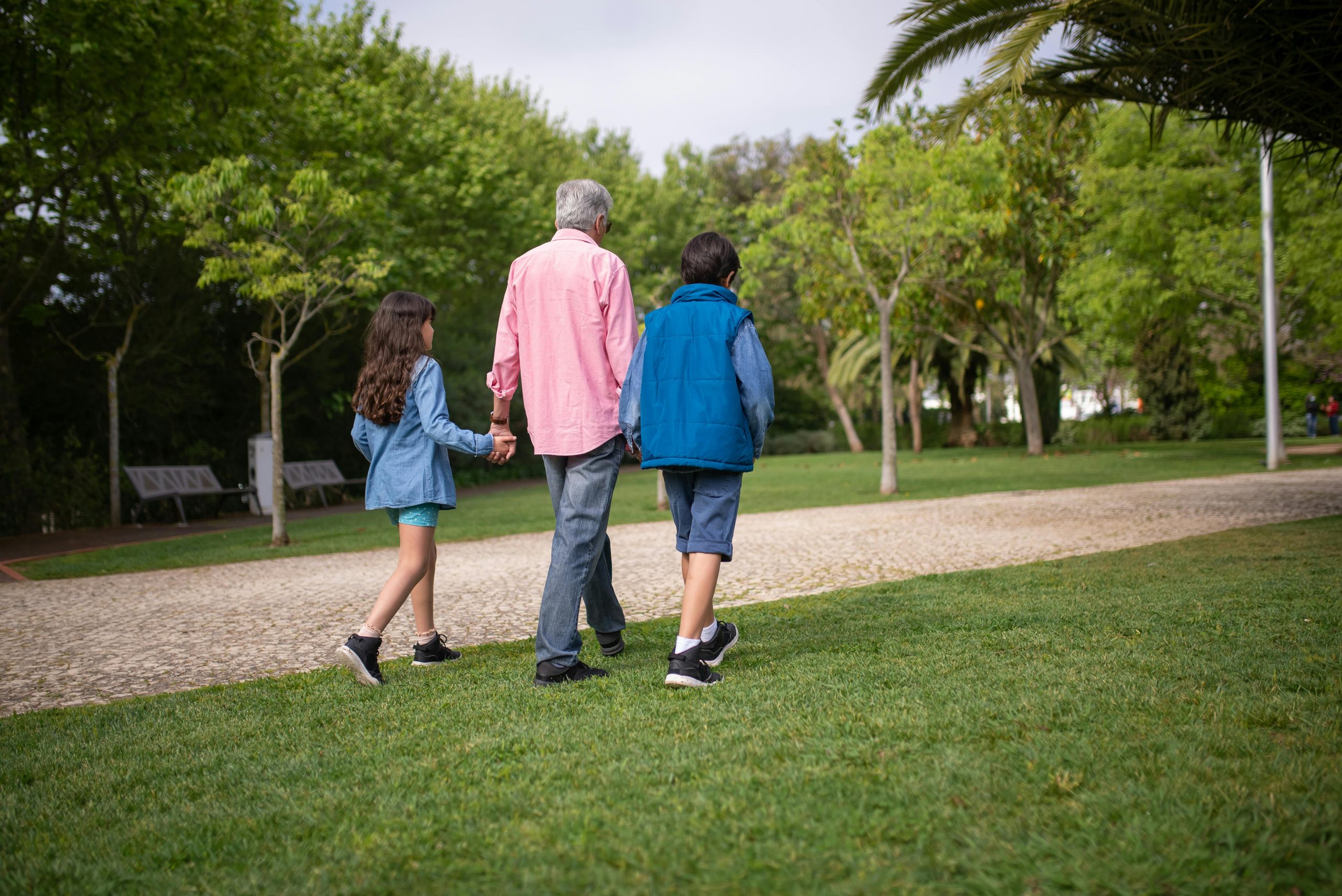 Elderly Man Walking at the Park with Grandchildren