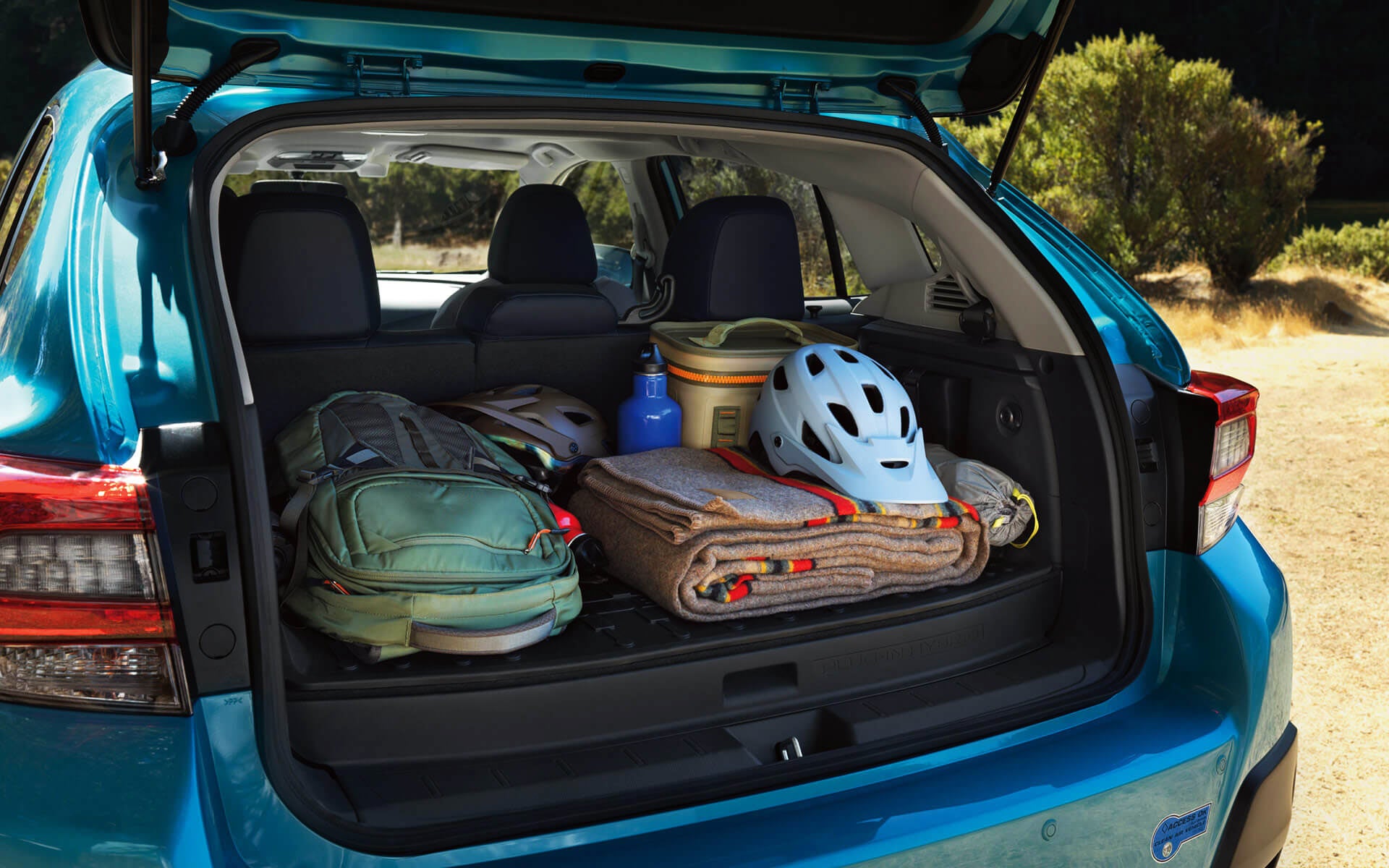 A backpack, blanket, and bike helmet in the rear cargo area of a Crosstrek Hybrid | John Kennedy Subaru in Plymouth Meeting PA